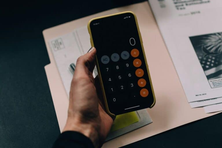 A person using a smartphone calculator beside financial paperwork